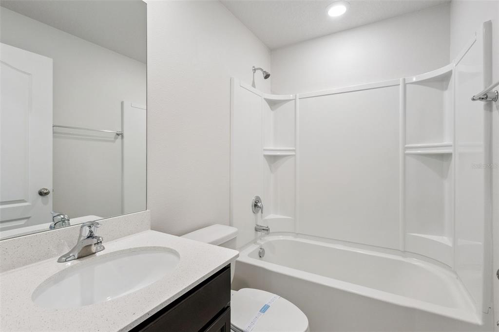 1613 Orne Street Mascotte, FL 34753 - Photo 16 of 31 a bathroom with a bathtub shower sink vanity mirror and toilet