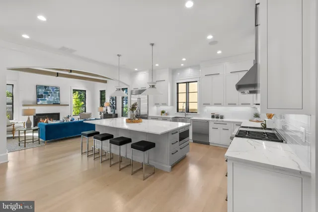 a kitchen with a stove a sink a kitchen island with chairs and wooden floor