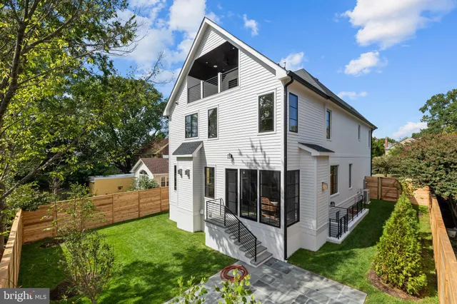 a view of a white house with a big yard plants and large trees