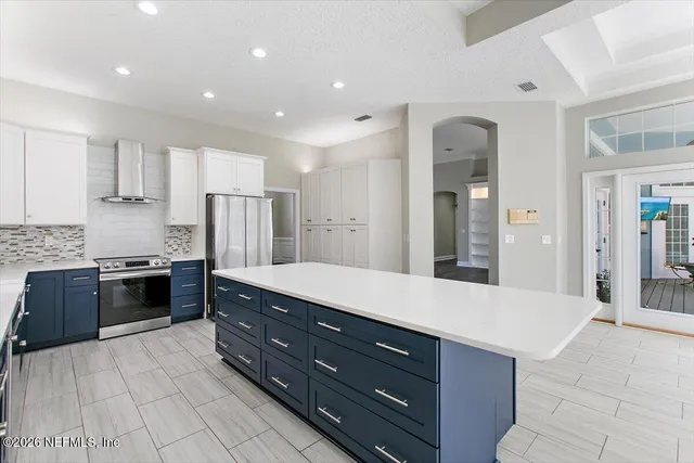 a large kitchen with a large counter top a sink stainless steel appliances and cabinets