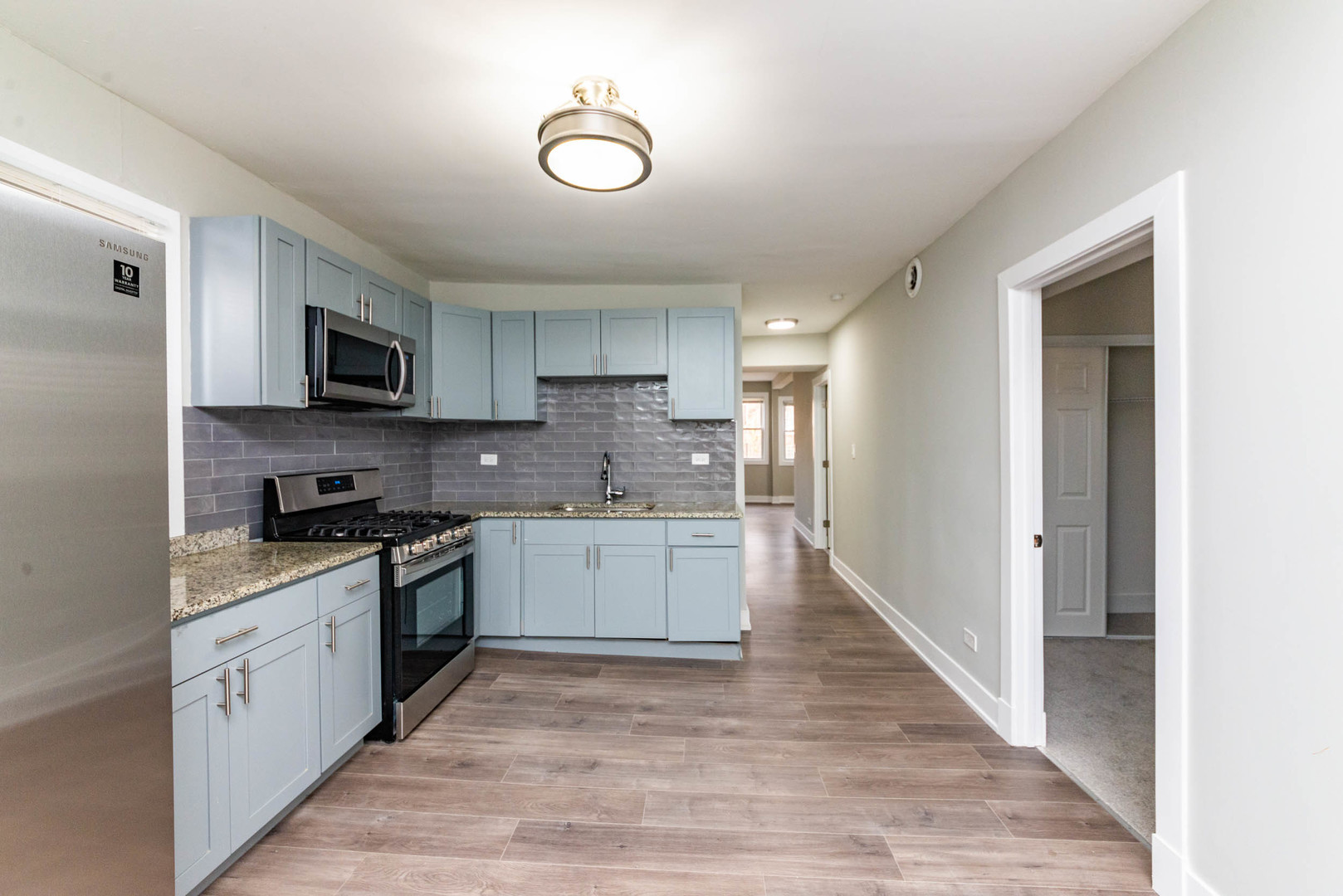 2923 North Avers Avenue, Unit 1 Chicago, IL 60618 - Photo 7 of 17 a kitchen with stainless steel appliances granite countertop a stove top oven a sink and white cabinets