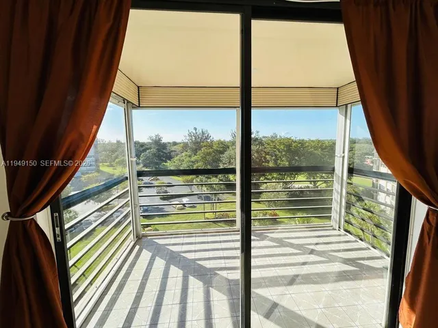 a view of a balcony with floor to ceiling window wooden floor with a table