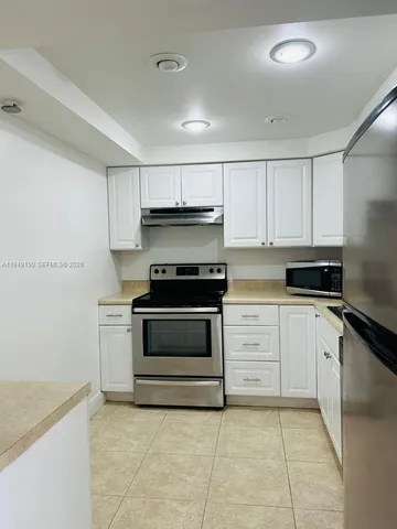 a kitchen with white cabinets and sink
