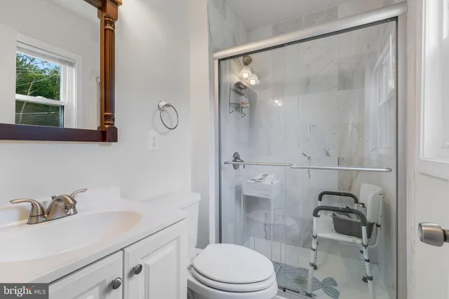 a bathroom with a sink vanity granite toilet and shower