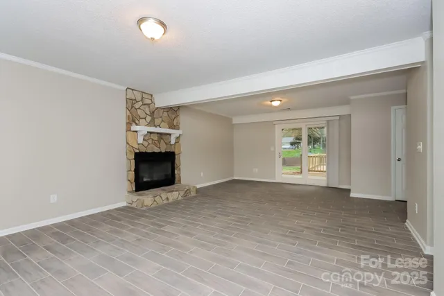 a view of an empty room with window and wooden floor