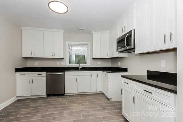 a kitchen with granite countertop white cabinets stainless steel appliances and a sink