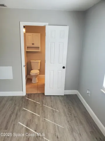 an empty room with wooden floor and a toilet