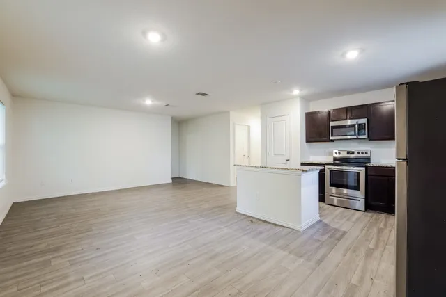 a kitchen with a sink wooden floor and stainless steel appliances