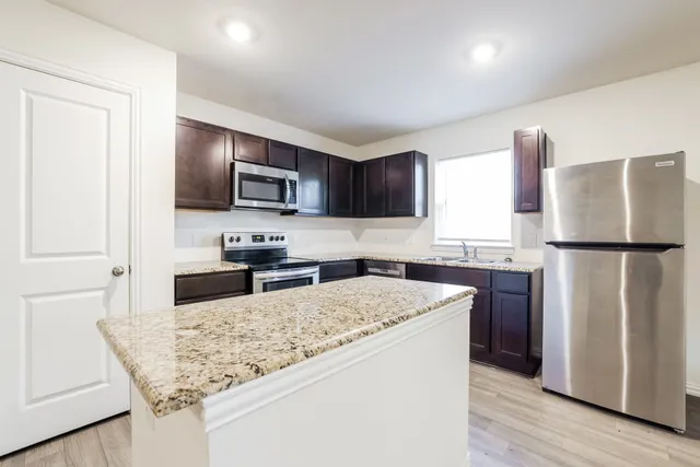 a kitchen with granite countertop a refrigerator and a stove top oven
