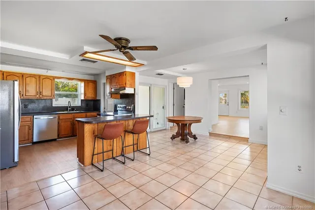 a kitchen with stainless steel appliances kitchen island granite countertop a sink a stove a dining table and chairs