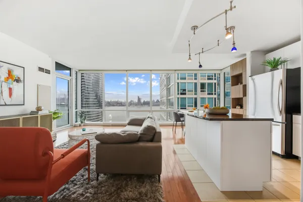 a living room with furniture a large window and kitchen view