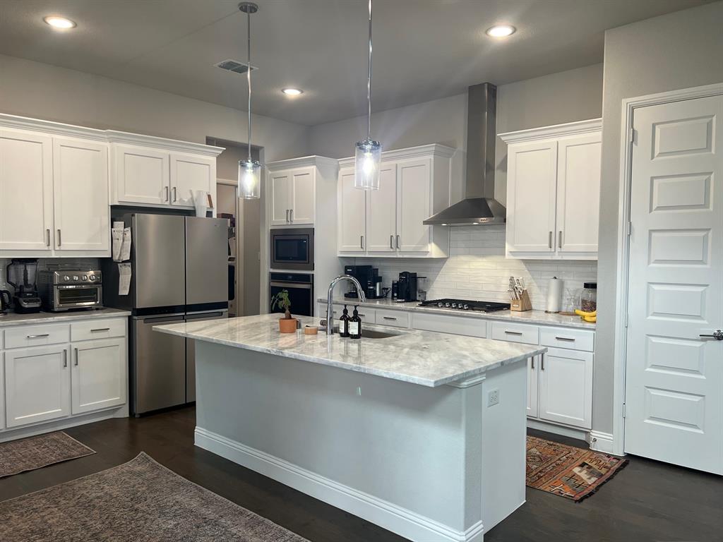 13244 Jonata Street Frisco, TX 75035 - Photo 3 of 20 a kitchen with a sink a stove a refrigerator and white cabinets