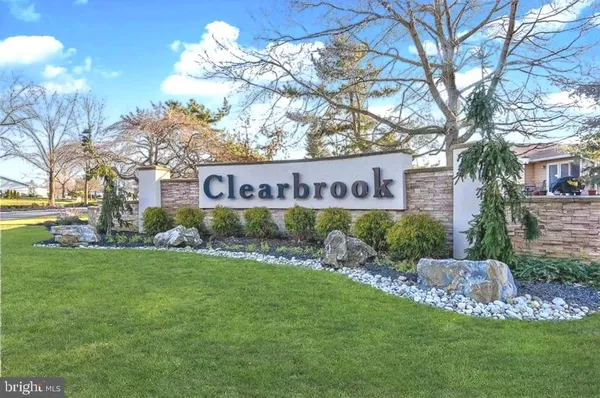 a view of front of a house with a street sign and a large tree