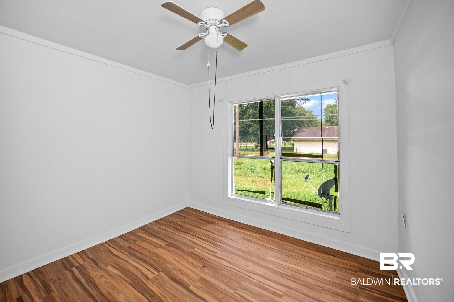 19575 Keller Road Foley, AL 36535 - Photo 13 of 17 Empty room with crown molding, wood finished floors, and a ceiling fan