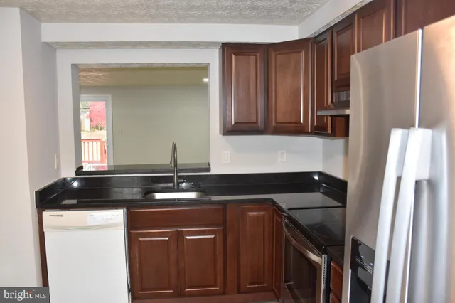 a kitchen with granite countertop a refrigerator and a sink