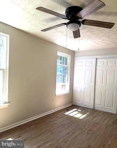 a view of a hallway with wooden floor and closet area