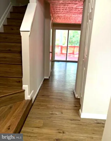 a view of a hallway with wooden floor and dining room view