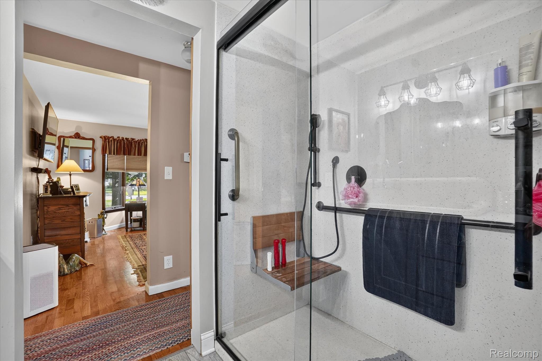 7178 Riegler Street Grand Blanc, MI 48439 - Photo 13 of 31 Walk-in shower with clear glass enclosure and black hardware, featuring a built-in wooden bench and black wall-mounted shower system