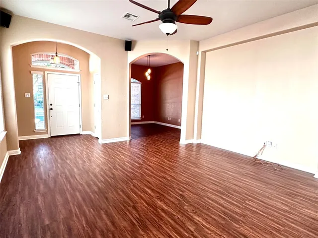 a view of an empty room with wooden floor and a window