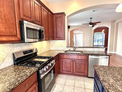 a kitchen with stainless steel appliances granite countertop a stove a sink and a microwave