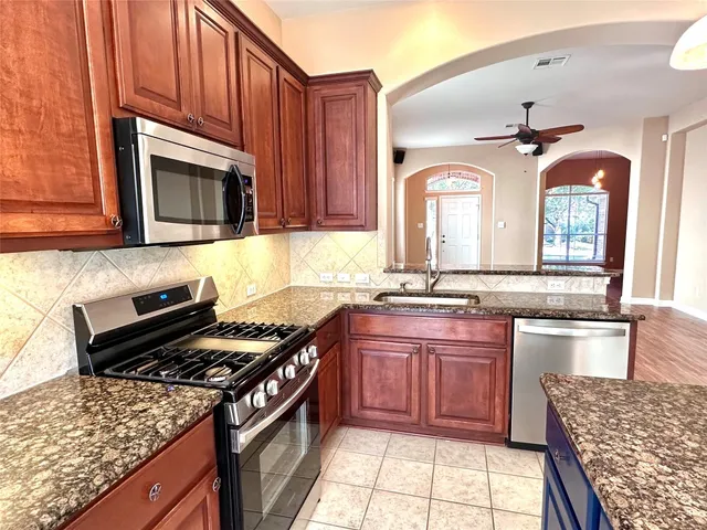 a kitchen with stainless steel appliances granite countertop a stove a sink and a microwave