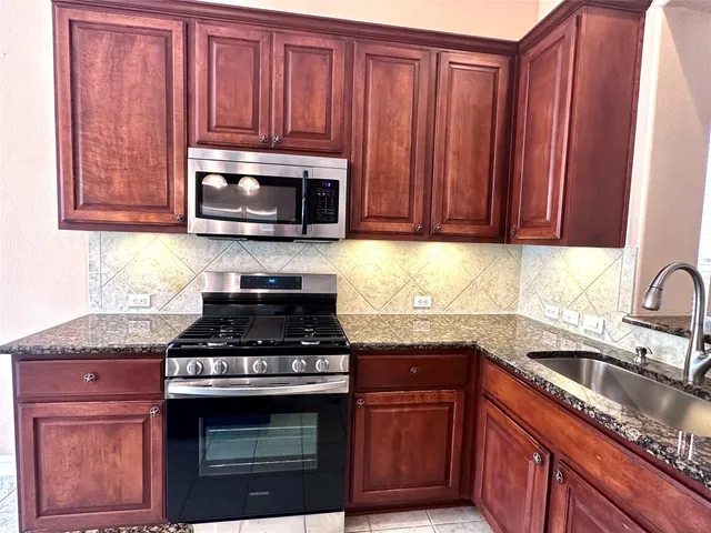a kitchen with granite countertop wood cabinets stainless steel appliances and a sink