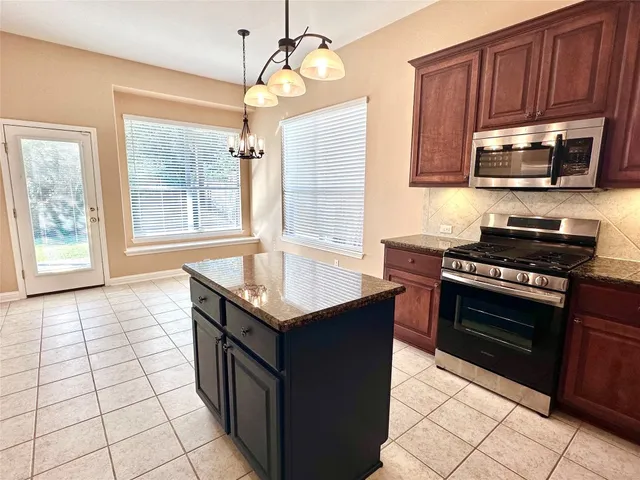 a kitchen with stainless steel appliances granite countertop a stove a sink and a microwave