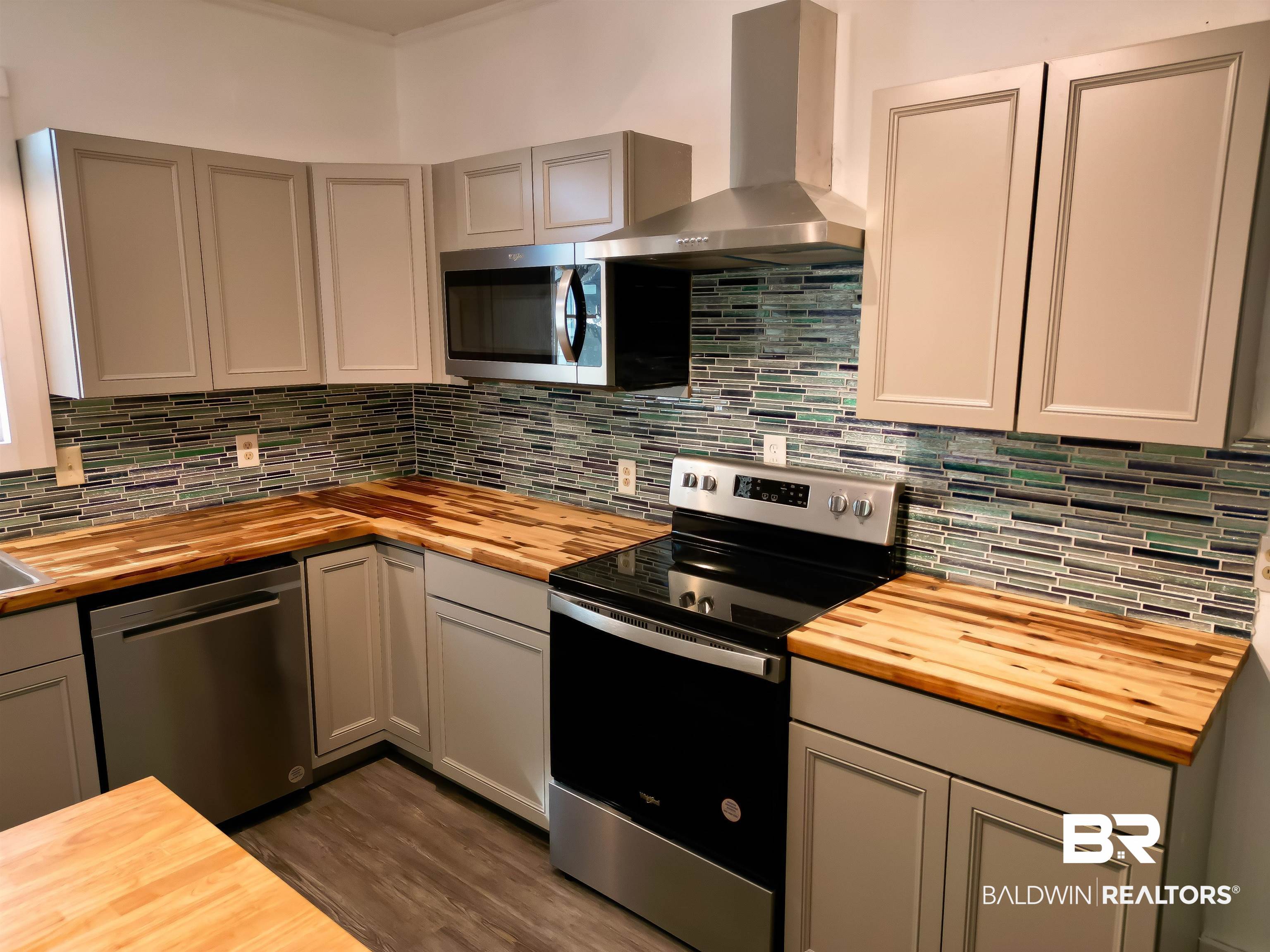 73 Liberty Street Monroeville, AL 36460 - Photo 6 of 29 Kitchen with appliances with stainless steel finishes, wooden counters, wall chimney range hood, and gray cabinetry