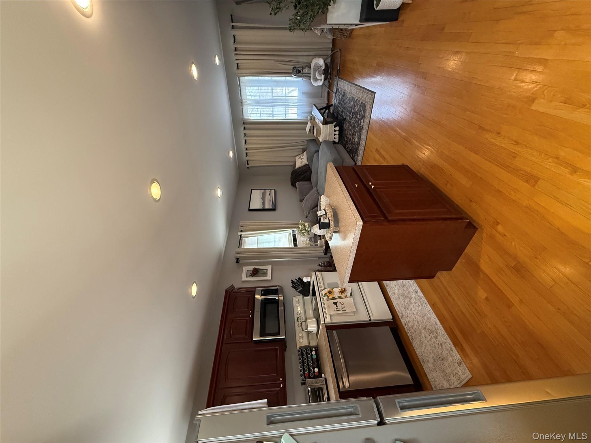 1009 Huckleberry Road North Bellmore, NY 11710 - Photo 15 of 24 a large white kitchen with stainless steel appliances granite countertop a stove oven a sink dishwasher and a refrigerator with wooden floor