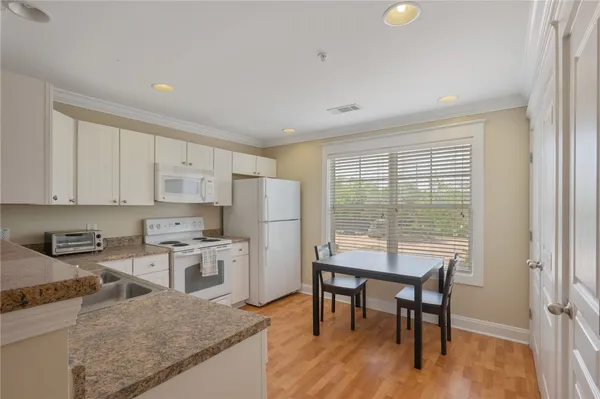 a kitchen with stainless steel appliances granite countertop a stove a refrigerator a kitchen island a table and chairs in it