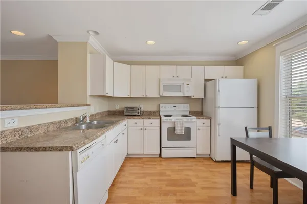 a kitchen with a sink a stove a refrigerator and white cabinets