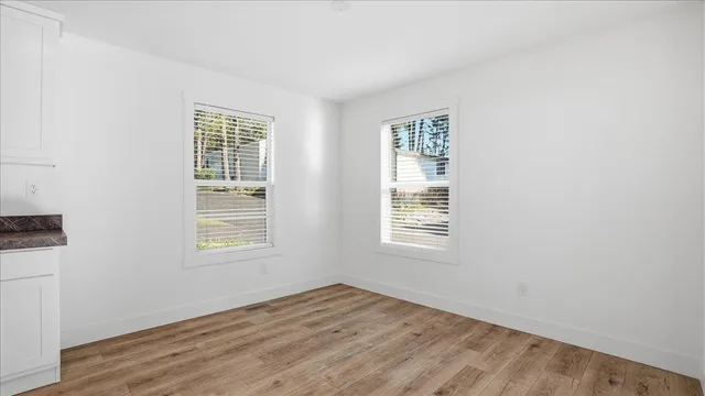 an empty room with wooden floor and windows