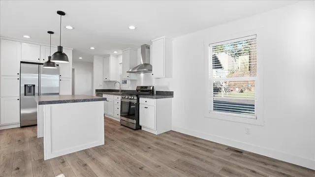 a kitchen with kitchen island white cabinets and stainless steel appliances