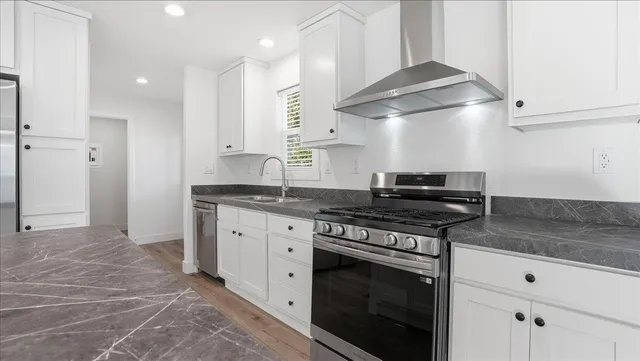 a kitchen with stainless steel appliances granite countertop a stove a sink and a refrigerator