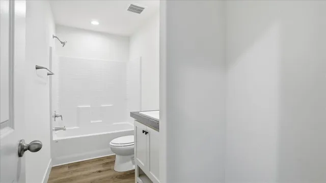 a bathroom with a granite countertop toilet a sink and a shower