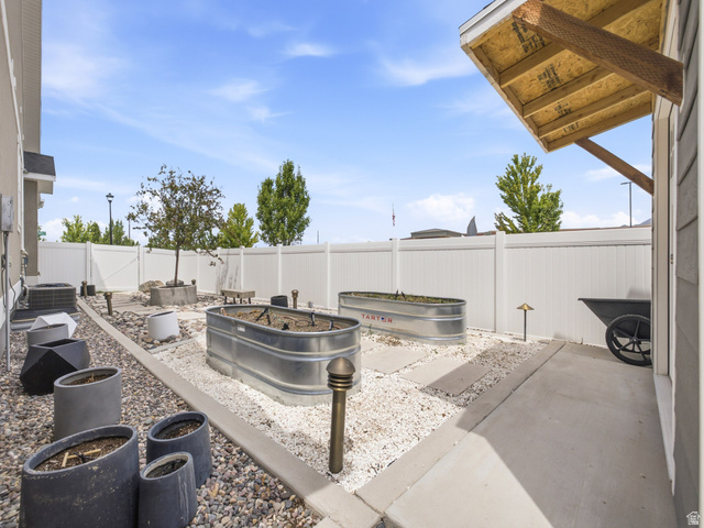 877 South Yarrow Drive Mapleton, UT 84664 - Photo 36 of 46 Private backyard space featuring a white vinyl fence, two galvanized planters, and a concrete patio section