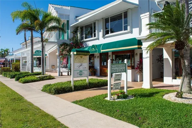 a view of a white house with a yard and palm trees