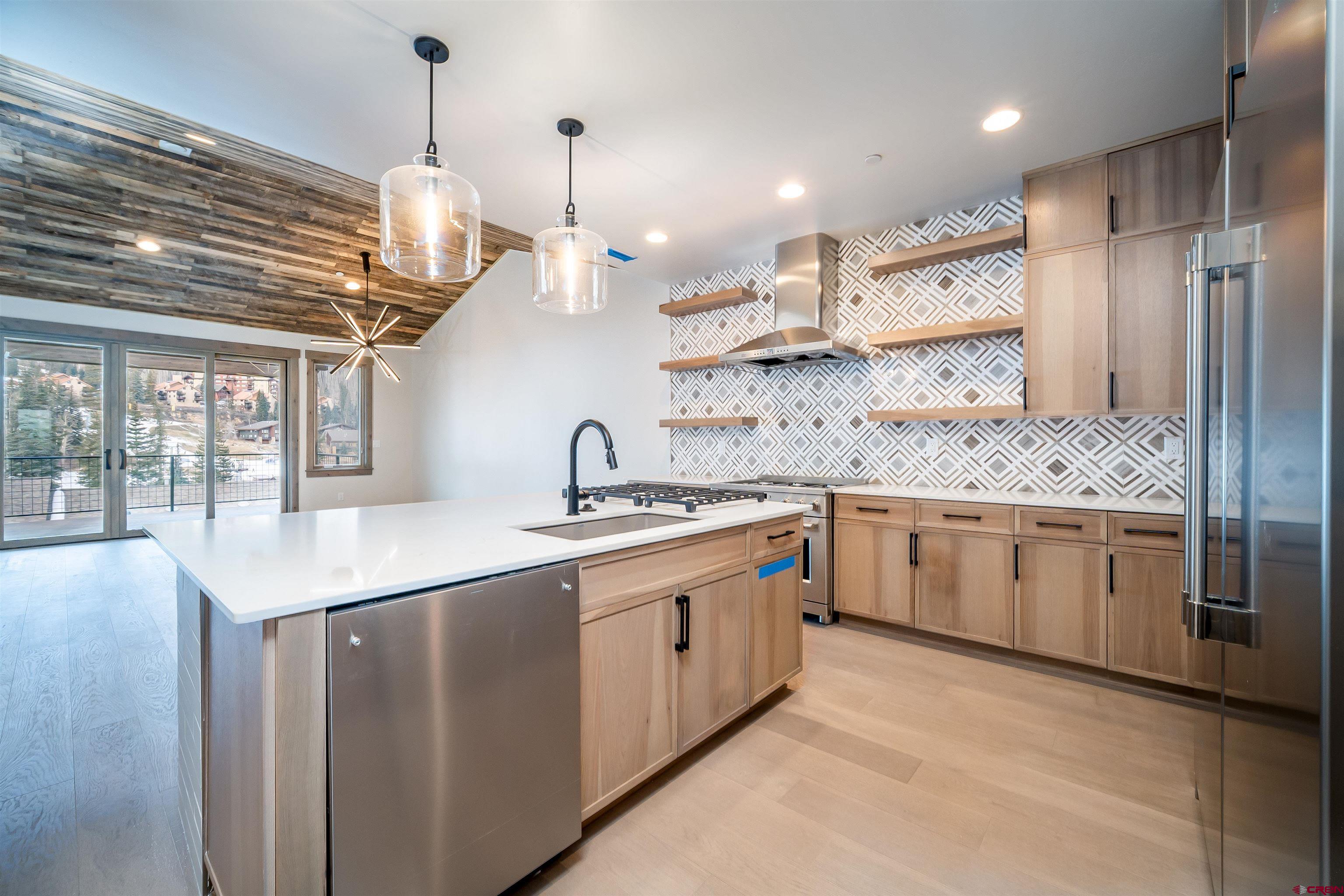 95 Travertine Trail Durango, CO 81301 - Photo 7 of 41 a kitchen with kitchen island granite countertop stainless steel appliances a sink a center island and a wooden floor