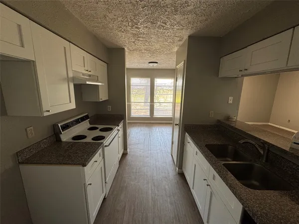 a kitchen with granite countertop a sink stove and cabinets