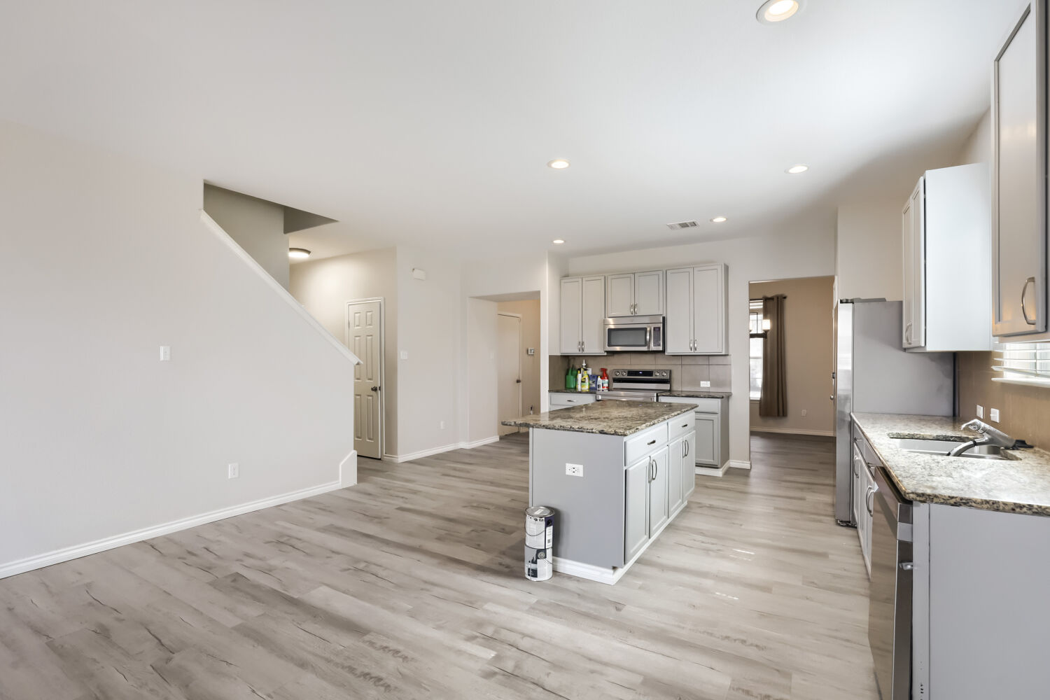 153 Marcheeta Way Leander, TX 78641 - Photo 6 of 17 Granite countertops and clean cabinetry anchor this open kitchen flowing into the living spaces.