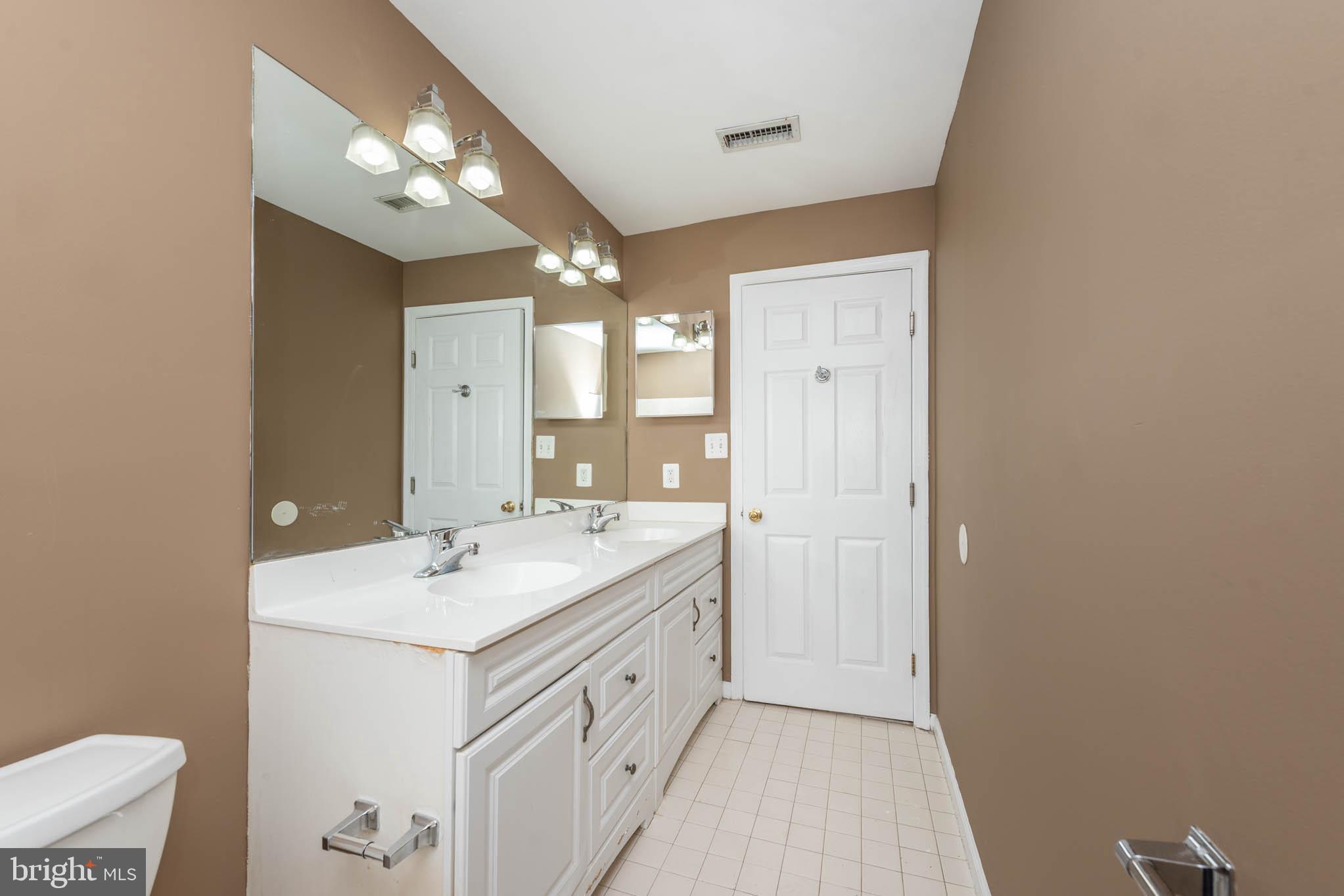 4021 Barrington Road Baltimore, MD 21207 - Photo 19 of 50 a spacious bathroom with a double vanity sink and a mirror
