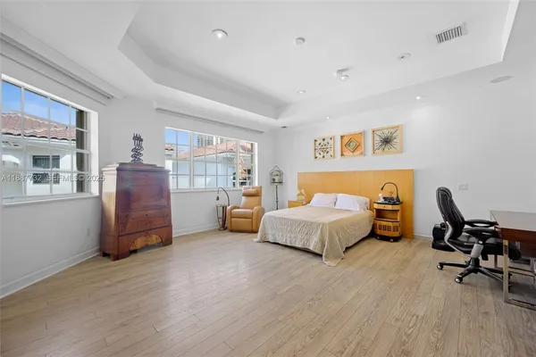 a spacious bedroom with a bed and dresser with wooden floor