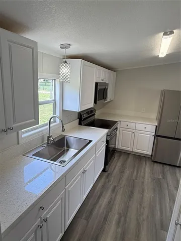 a kitchen with granite countertop a sink a counter space appliances and cabinets