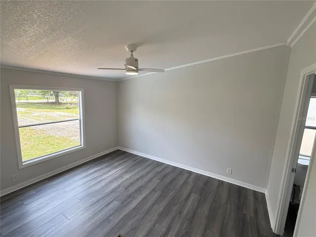 an empty room with wooden floor fan and windows
