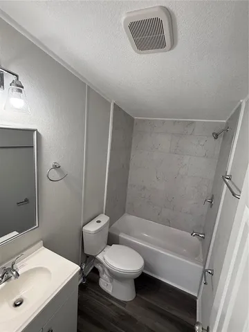 a bathroom with a granite countertop toilet a sink and a bathtub