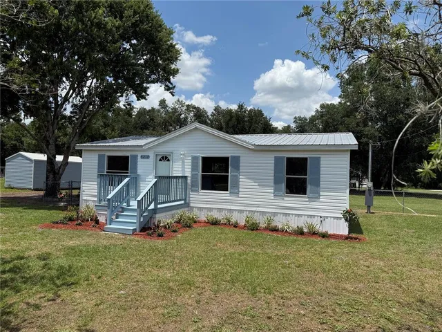 a front view of house with a garden and trees