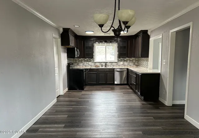 a kitchen with stainless steel appliances granite countertop a sink and a wooden floor
