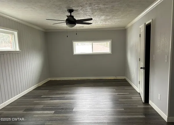 a view of empty room with wooden floor and fan