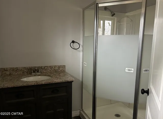 a bathroom with a granite countertop sink and shower