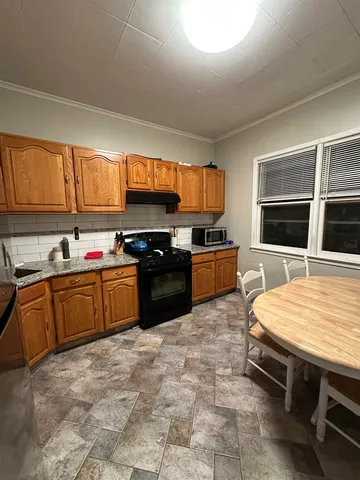 a large kitchen with kitchen island granite countertop a stove top oven a sink a counter space and cabinets